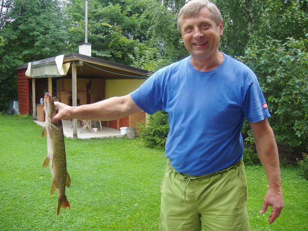 Owner of River Rose Guesthouse with a pike caught from the Navesti River. You can go fishing without leaving the yard.